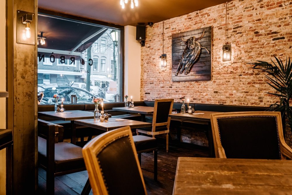 Warm verlichte zaal met bakstenen muur, kaarsen en het Carbon-merk, sfeerbeeld vestiging Zuid