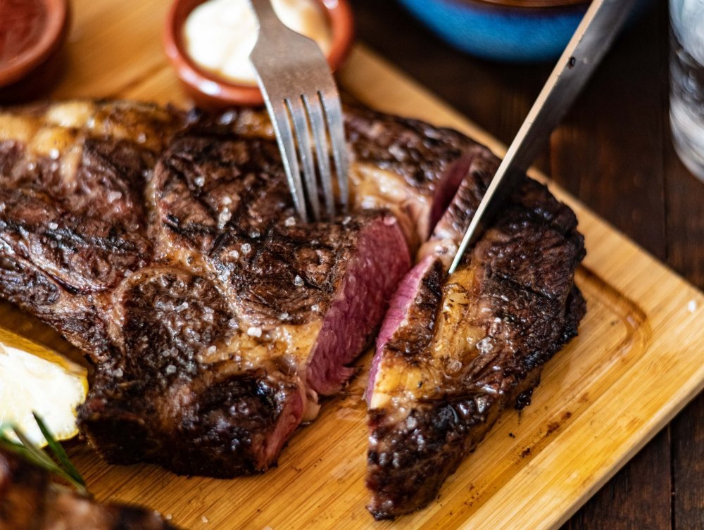 Op het vuur gegrilde steak met grillstrepen, aangesneden op een houten plank